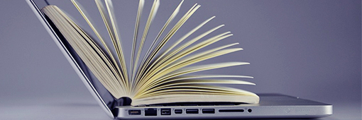 Escrita digital e tradicional - Livro aberto em cima de um computador notebook